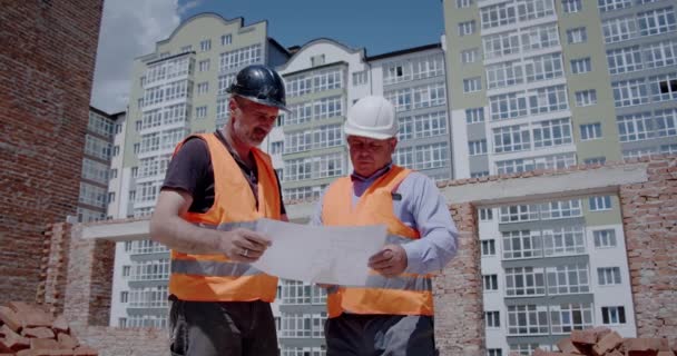 Construction manager and engineer working on building site, construction workers look at the drawings - Metraje, vídeo