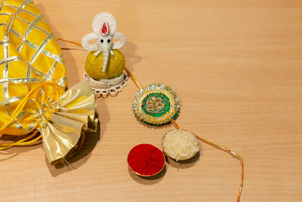 Indian festival, Raksha Bandhan background with an elegant colorful Rakhi, Gift, Rice Grains and Kumkum. A traditional Indian wrist band which is a symbol of love between Brothers and Sisters. - Photo, Image