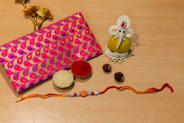 インドの祭り、ラクシャバンダンの背景には、エレガントなカラフルなラキ、ギフト、米粒、クムクムがあります。兄弟姉妹間の愛の象徴である伝統的なインドの手首バンド. - 写真・画像