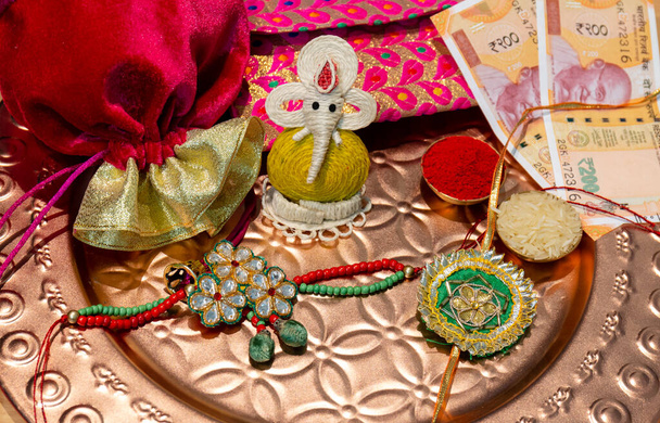 Indisches Fest, Raksha Bandhan Hintergrund mit einem eleganten bunten Rakhi, Geschenk, Reiskörner und Kumkum. Ein traditionelles indisches Armband, das ein Symbol der Liebe zwischen Brüdern und Schwestern ist. - Foto, Bild