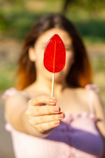 fiatal lány kezében egy piros nyalóka - Fotó, kép