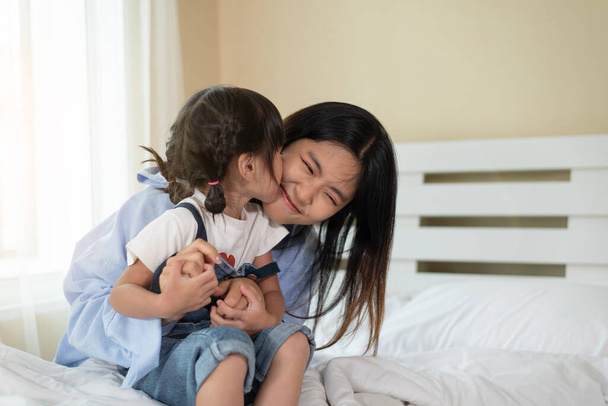 Happy Asian family loving children, kid and her sister relaxing together in bed, love and happiness concept - Valokuva, kuva