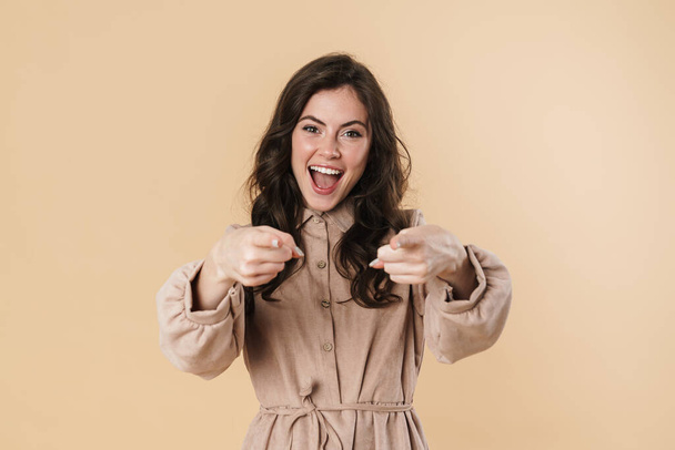 Image of delighted cute woman smiling and pointing fingers at camera isolated over beige background - Φωτογραφία, εικόνα