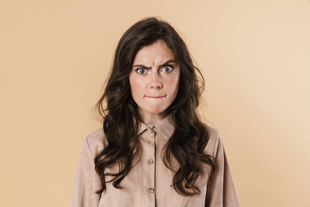 Image of angry cute woman posing and looking at camera isolated over beige background - Φωτογραφία, εικόνα