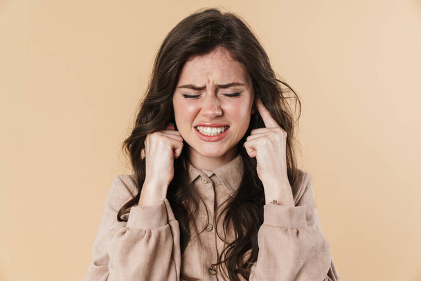 Image of unhappy brunette nice woman plugging her ears isolated over beige background - Φωτογραφία, εικόνα