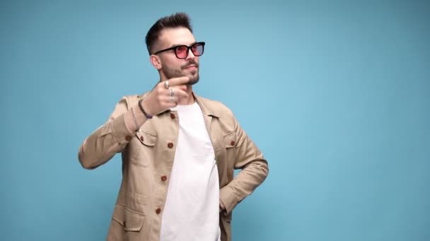 pensive casual fashion model in jacket thinking, scratching head and trying to remember, pointing finger and holding palms in the air, applauding and laughing on blue background - Footage, Video