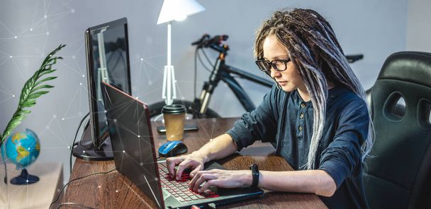 Moderni nuori naisohjelmoija kirjoittaa ohjelmakoodia kannettavaan tietokoneeseen kotona. Etätyö IT-alalla. Ohjelmistojen kehittämisen käsite. - Valokuva, kuva