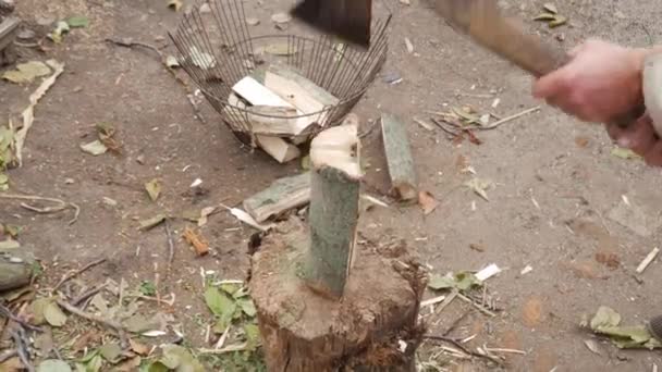Opa in einem armen russischen Dorf hackt Holz mit der Axt auf den Baumstumpf. Herbstdorfhof. Brennholz für den Winter ernten. - Filmmaterial, Video