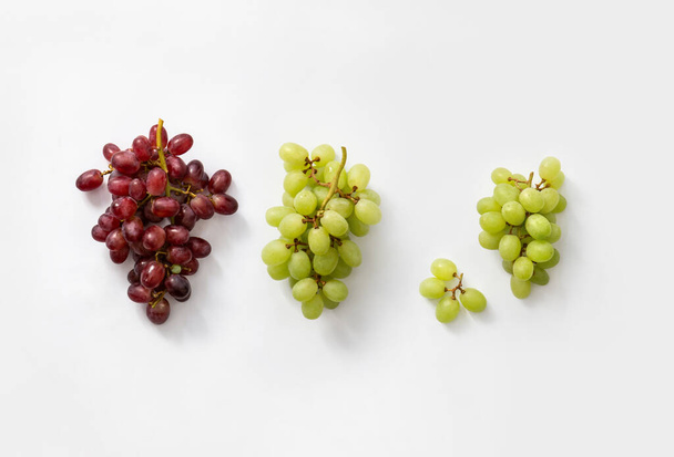 drie trossen rode en witte druiven op witte achtergrond - Foto, afbeelding