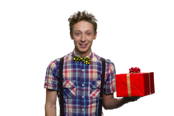 Caucasian teenage boy is holding red gift box on his hand. - Φωτογραφία, εικόνα