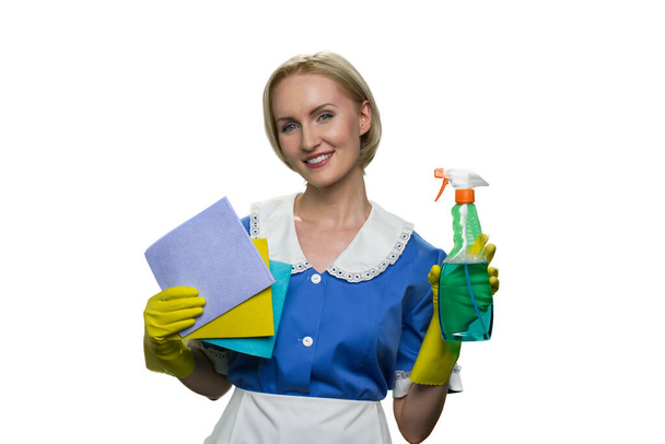 Joyeux jeune femme de ménage tenant chiffon et pulvérisation sur fond blanc. - Photo, image