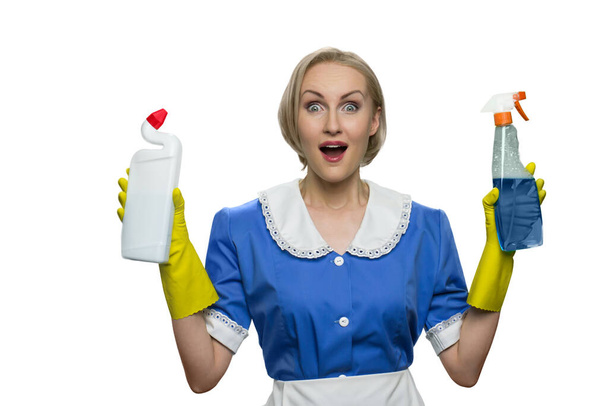 Surprised maid with open mouth holding cleaner spray and toilet disinfectant on white background. - Photo, Image