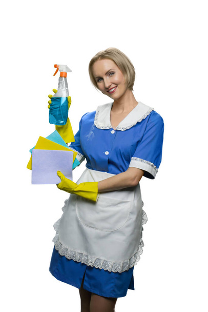 Rubia criada en guantes de goma amarilla demostrando limpiador spray y plumas sobre fondo blanco
. - Foto, imagen