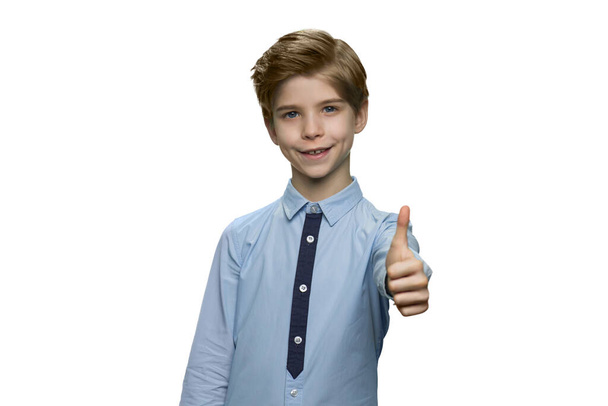 Uśmiechnięty chłopiec w niebieskiej koszuli pokazuje znak OK z kciukiem w górze. - Zdjęcie, obraz
