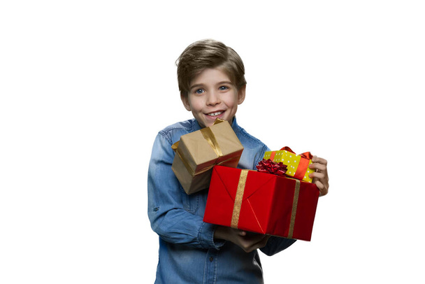 Teenage boy in denim clothes holding lots of present boxes on white background. - Foto, imagen