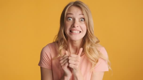 Attractive blond girl emotionally rejoicing and sadly looking in camera because of fault over colorful background. Different emotions - Footage, Video
