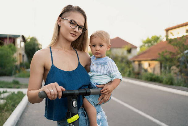Мать и сын едут на электрическом скутере - Фото, изображение