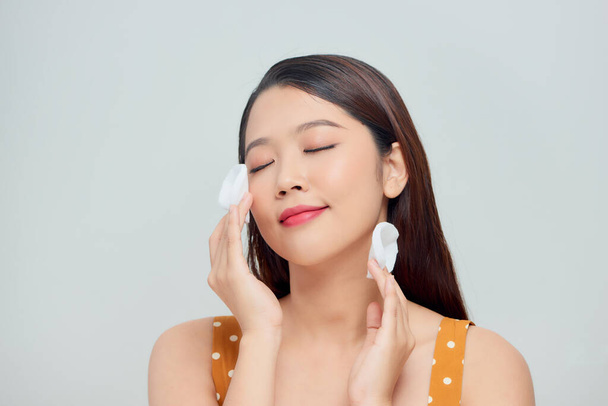 Photo de femme asiatique tient des tampons de coton près du visage isolé sur fond blanc - Photo, image