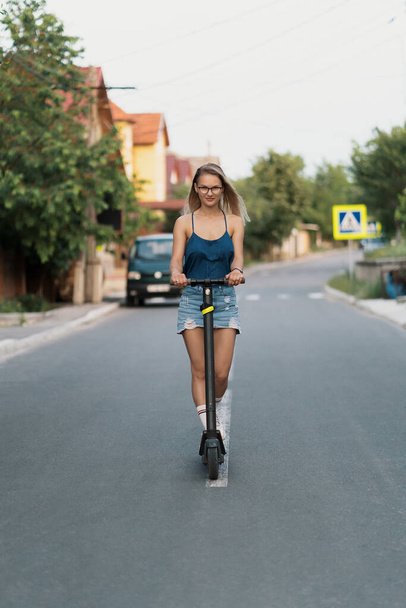 Millenniumi nő lovaglás elektromos robogó az utcán - Fotó, kép
