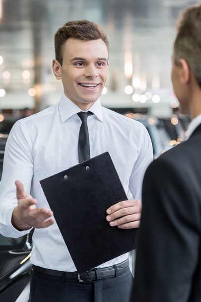 Handsome young classic car salesman talking to a customer - Photo, image