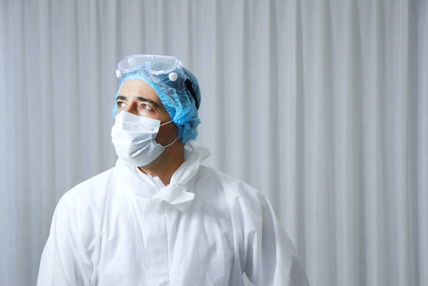 Sperimentatore scientifico caucasico uomo Indossare guanti di gomma protettiva blu e in piedi in laboratorio. Scienza e merluzzo bianco19 visus Concept. - Foto, immagini
