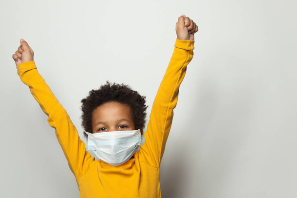Retrato de menino negro feliz na máscara protetora médica de mãos erguidas
 - Foto, Imagem