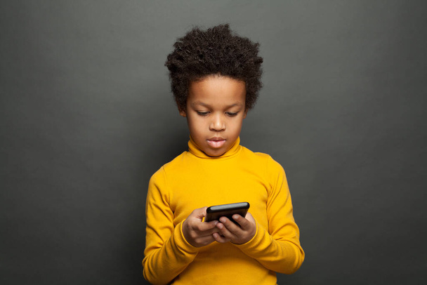 African American child holding smartphone and playing - Valokuva, kuva