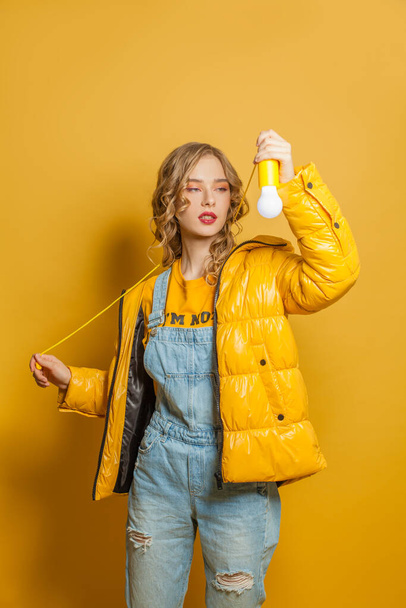 Fashion woman with lightbulb on yellow background - Fotoğraf, Görsel