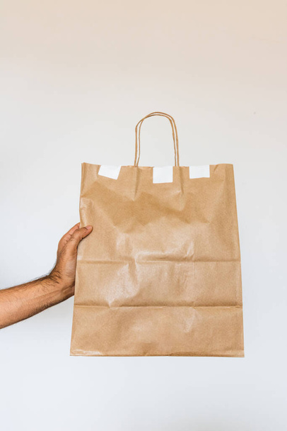 Holding a paper bag isolated. Delivery home food app concept image. - Zdjęcie, obraz