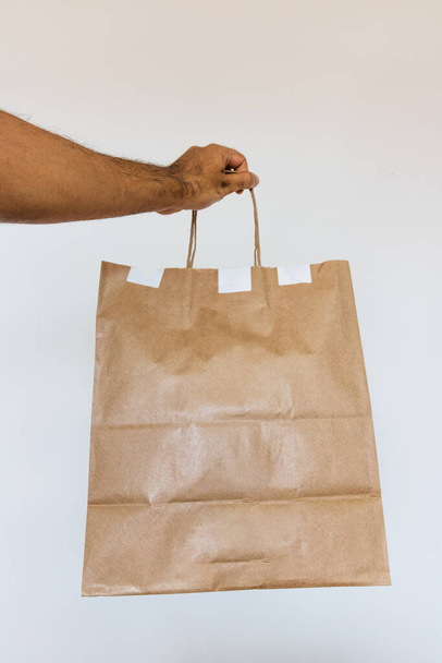 Κρατώντας μια χάρτινη σακούλα απομονωμένη. Παράδοση σπίτι τροφίμων app έννοια εικόνα. - Φωτογραφία, εικόνα