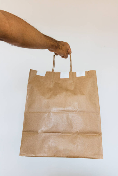 Trzymanie papierowej torby w izolatce. Dostawa domu żywności aplikacji koncepcja obrazu. - Zdjęcie, obraz