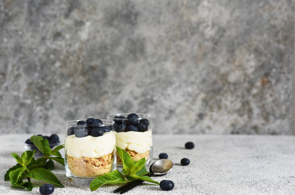 Cheesecake with cookies and berries in a glass on a light concrete background. - Photo, Image