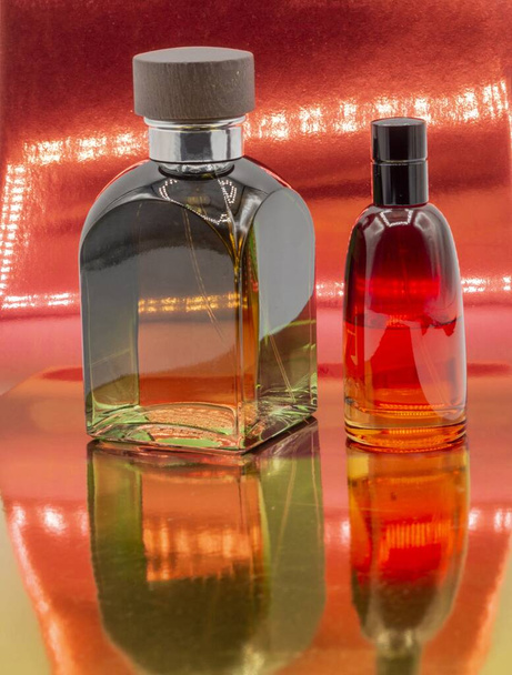A vertical shot of two perfume glass bottles on red background - Фото, изображение