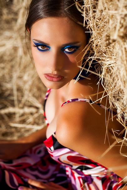 Portrait of a young beautiful woman with bright makeup posing on a mown wheat field - Foto, afbeelding