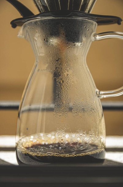 A vertical shot of a brewed black coffee in a glass Chemex coffeemaker - Fotoğraf, Görsel