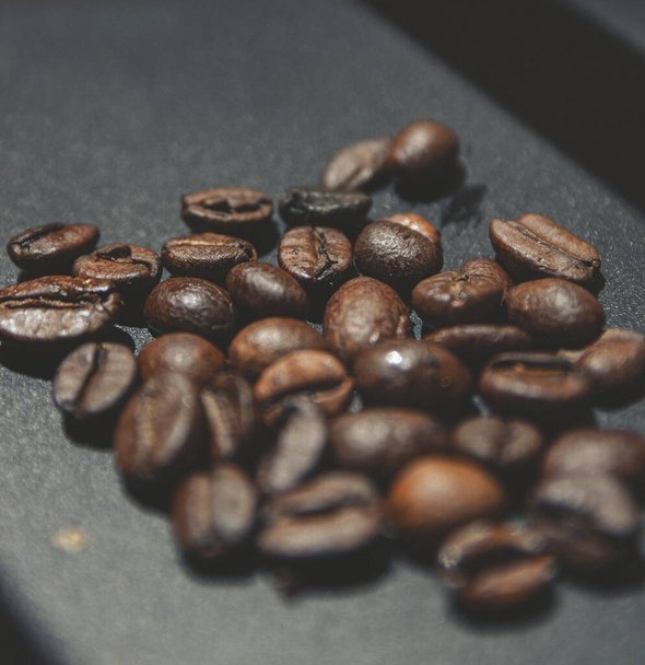 A closeup shot of roasted coffee beans on a black surface - Fotoğraf, Görsel