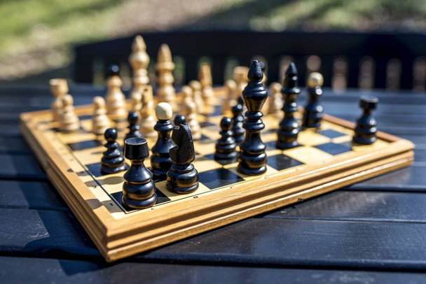 A closeup shot of the chessboard with chess pieces on blurred background under a sunlight - Foto, immagini