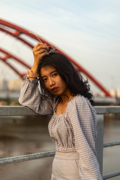 A vertical shot of an attractive Asian female standing on the bridge - Foto, Imagen