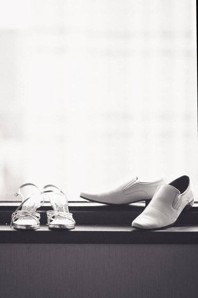Zapatos de novia y novio en la ventana de cristal en la ceremonia de boda del hotel
 - Foto, imagen