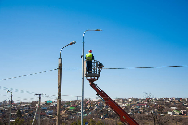 Elektrikçiler elektrik direğindeki elektrik hattını tamir ediyorlar. - Fotoğraf, Görsel