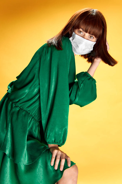 Žena v módních šatech pózuje v lékařské masce virus covid-19 - Fotografie, Obrázek