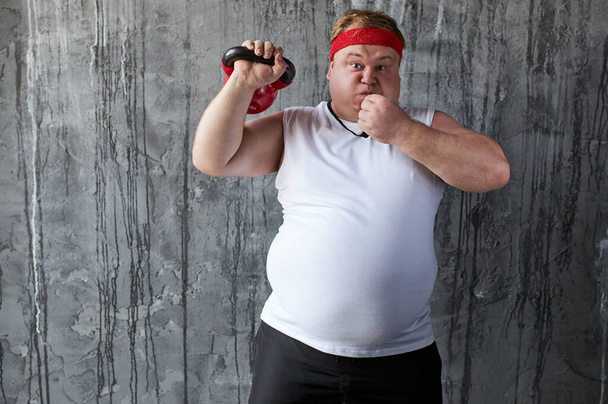 太った強い男性はケトルベルを使う能力を示しています - 写真・画像