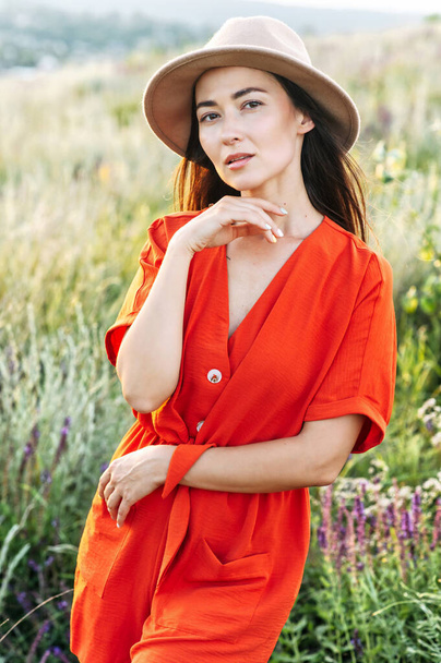 Beautiful woman in hat walks in the flower field - Foto, Imagen