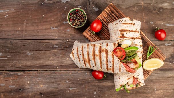 Tortilla wrap with asparagus, cherry tomatoes, avocado, chicken fillet and fresh salad. healthy food. Top view. banner, menu recipe place for text. - Photo, Image