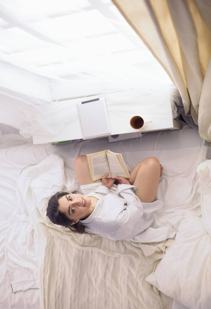 Portrait of woman using tablet and drinking coffee while sitting on the bed in the morning - Fotoğraf, Görsel