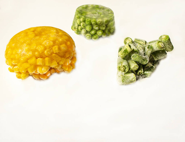 Замороженные овощи крупным планом на белом фоне. Холодная кукуруза, зеленый горох, нарезанные зеленые бобы. Здоровое питание, сырая веганская еда. Копирование пространства
 - Фото, изображение