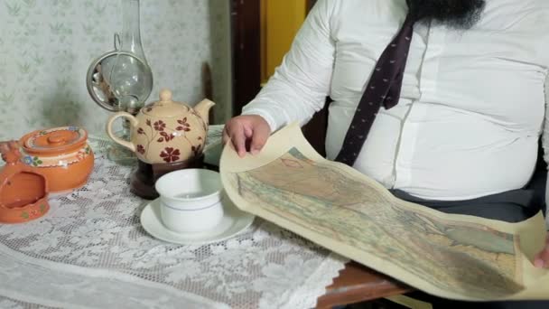 Barbudo hombre desenrolla un pergamino y comienza a mirar el mapa viejo
 - Metraje, vídeo