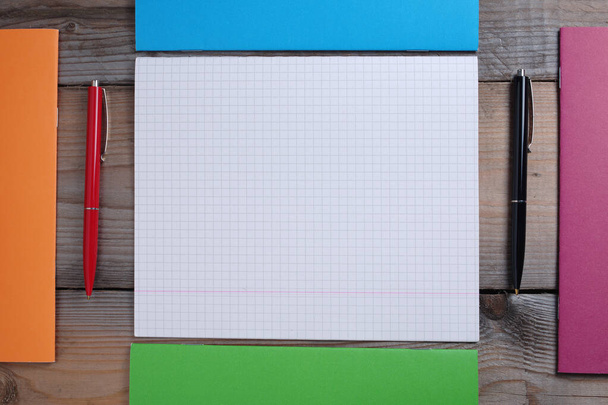 Cuadernos coloridos de la escuela y bolígrafos sobre fondo de madera viejo, vista superior
 - Foto, imagen