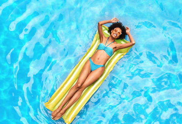 Letní prázdniny. Millennial černošky dívka relaxační na lilo na venkovním bazénu za slunečného dne, horní pohled - Fotografie, Obrázek