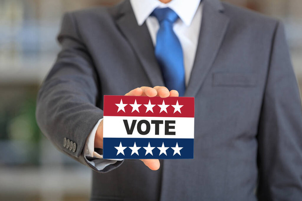 USA elections, Man holding a card, VOTE text message on american flag colors with patriotic stars. Vote on US of America election day concept. - Photo, Image